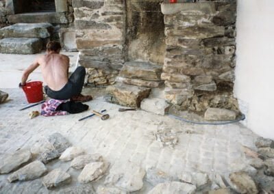 France Fortified Farm House: local artisan repairing wall reusing stone